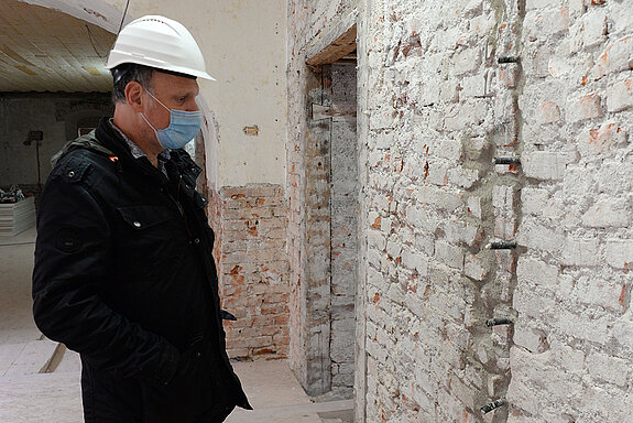 Ulrich Setzwein, Projektleiter im Hochbauamt für die Generalsanierung des Asamgebäudes, studiert das Mauerwerk. (Foto: Stadt Freising)