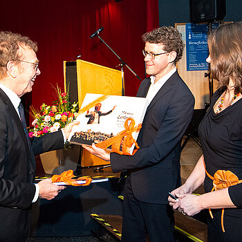 Mit einem Fotoalbum aus seiner verdienstvollen Ära als Schulleiter und einem Gutschein für einen Dirigentenkurs bedenkt die Musikschule ihren ehemaligen Chef. (Foto: Stadt Freising)