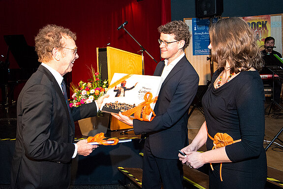 Mit einem Fotoalbum aus seiner verdienstvollen Ära als Schulleiter und einem Gutschein für einen Dirigentenkurs bedenkt die Musikschule ihren ehemaligen Chef. (Foto: Stadt Freising)