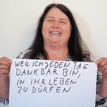 Stadtratsmitglied Ingrid Kaiser. Foto: Stadt Freising Eine Frau in einem weiß/schwarzen Hemd zeigt ein Schild mit der Aufschrift "weil ich jeden Tag dankbar bin in ihr leben zu dürfen"