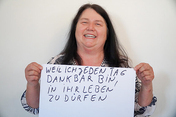 Stadtratsmitglied Ingrid Kaiser. Foto: Stadt Freising Eine Frau in einem weiß/schwarzen Hemd zeigt ein Schild mit der Aufschrift "weil ich jeden Tag dankbar bin in ihr leben zu dürfen"