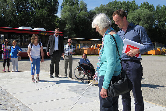 Die neue Lösung für Entwässerung und Blindenleitsystem wird mit Blindenstock und Rollstuhl getestet. (Foto: Stadt Freising)