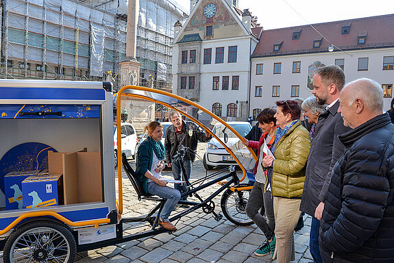 Probesitzen auf dem neuen E-Lastenfahrrad: Klimaschutzmanagerin Marie Hüneke erläutert die Einsatzmöglichkeiten des Info-Mobils. (Foto: Stadt Freising)