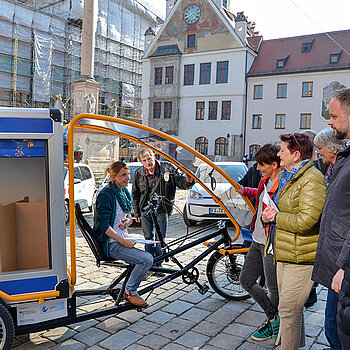 Probesitzen auf dem neuen E-Lastenfahrrad: Klimaschutzmanagerin Marie Hüneke erläutert die Einsatzmöglichkeiten des Info-Mobils. (Foto: Stadt Freising)