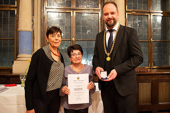 OB Tobias Eschenbacher überreicht an Martha Gebele (Mitte) stellvertretend die Urkunde für Lia Köhnlein. (Foto: Stadt Freising)