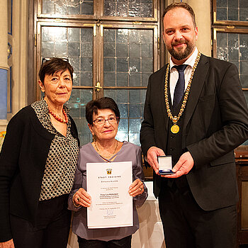 OB Tobias Eschenbacher überreicht an Martha Gebele (Mitte) stellvertretend die Urkunde für Lia Köhnlein. (Foto: Stadt Freising)