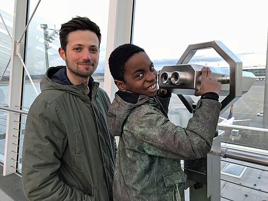 Balu Aleks und Mogli an einem ein Fernrohr am Flughafen.