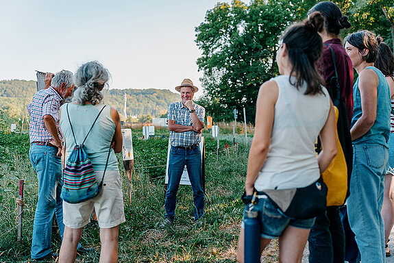 Mehrere Menschen stehen in einem Feld. 