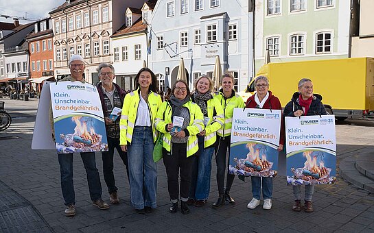 Informierten die Passanten über die Problematik: von l.n.r. Jürgen Maguhn, Sepp Beck, Elisabeth Hofmann, Dr. Alexandra Feigel, Kristin Schreiber, Anja Finkenzeller, Christel Orthen-Schmuker, Carolin Plötz. Foto: Wurzer Umwelt GmbH Menschen teilweise in gelben Warnwesten, teilweise mit Sandwich-Plakaten stehen in der Stadt und lächeln in die Kamera