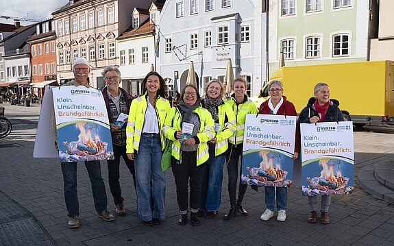Informierten die Passanten über die Problematik: von l.n.r. Jürgen Maguhn, Sepp Beck, Elisabeth Hofmann, Dr. Alexandra Feigel, Kristin Schreiber, Anja Finkenzeller, Christel Orthen-Schmuker, Carolin Plötz. Foto: Wurzer Umwelt GmbH Menschen teilweise in gelben Warnwesten, teilweise mit Sandwich-Plakaten stehen in der Stadt und lächeln in die Kamera