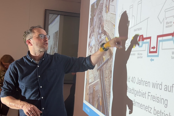 Tobias Grießl, Freisinger Stadtwerke Versorgungs-GmbH erklärt den Ausbau des Freisinger Fernwärmenetzes.Foto: Rainer Teschner Ein Mann im dunkelblauen Hemd steht vor einer Präsentation und zeigt darauf