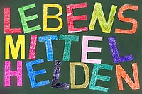 Bunte Gro&szlig;buchstaben in verschiedenen Farben, teilweise leicht schief auf einer Tafel
