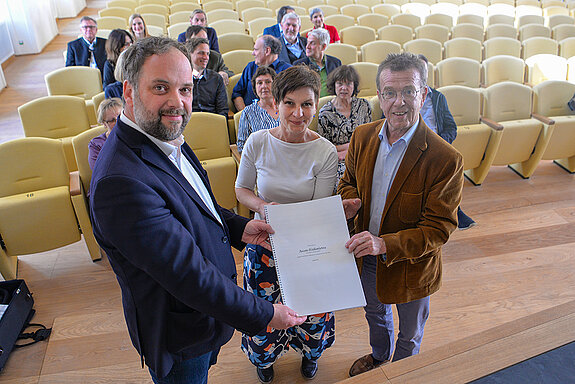 Martin Keeser (rechts) übergibt die Partitur der von ihm komponierten Asam-Sinfonietta an OB Tobias Eschenbacher und Kulturreferentin Susanne Günthe. (Foto: Stadt Freising)