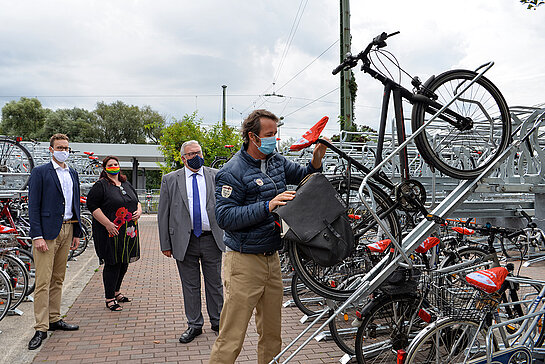 Marco Ladenthin und Mareike Schoppe (DB) sowie MdB Erich Irlstorfer (v.l.) schauen interessiert zu, wie Freisings Mobilitätsreferent Karl-Heinz Freitag das Rad auf den Bügel setzt. (Foto: Stadt Freising)