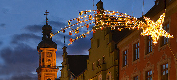 Das Bild zeigt eine beleuchtete Sternschnuppe in der Altstadt Freising und den Turm der Pfarrkirche St. Georg.
