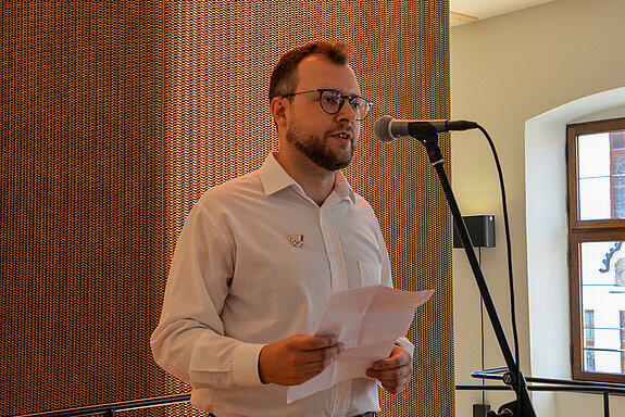 Das Foto zeigt Freising Kulturreferent Nico Heitz stehend vor einem Mikrofon.