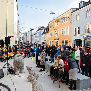 Blick auf den neuen Stadtplatz mit Bärengruppe, Granitsteinen zum Sitzen, die auch der Verkehrsberuhigungdienen, sowie der von Kindern und Gästen bevölkerten Rundbank um den neu gepflanzten Baum. (Foto: Stadt Freising)