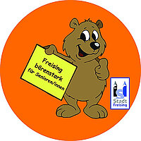 Bär mit Stadtlogo und Schild: "Freising bärenstark für Senioren/innen"