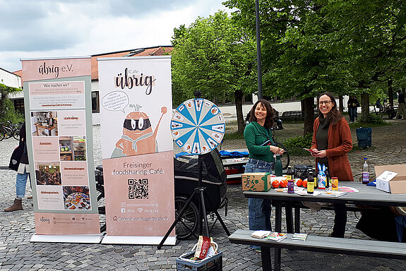 2 Rollups und 2 lachende Frauen hinter einem Tisch mit Material