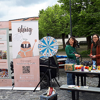 2 Rollups und 2 lachende Frauen hinter einem Tisch mit Material