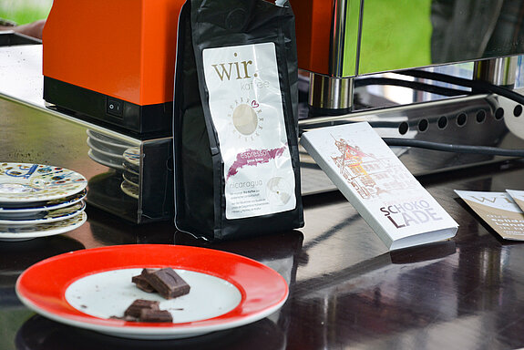eine Packung fairer Espresso aus Nicaragua, die schön gestaltete Schokoladenbanderole mit Zeichnung des Rathauses und ein Teller mit Schokoladenstückchen