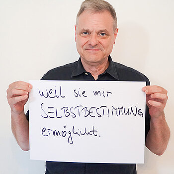 Stadtratsmitglied Peter Warlimont. Foto: Stadt Freising Ein Mann in einem schwarzen T-shirt zeigt ein Schild mit der Aufschrift "weil sie mir SELBSTBESTIMMUNG ermöglicht."