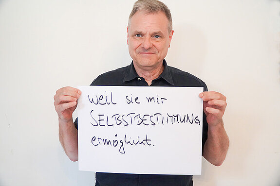 Stadtratsmitglied Peter Warlimont. Foto: Stadt Freising Ein Mann in einem schwarzen T-shirt zeigt ein Schild mit der Aufschrift "weil sie mir SELBSTBESTIMMUNG ermöglicht."