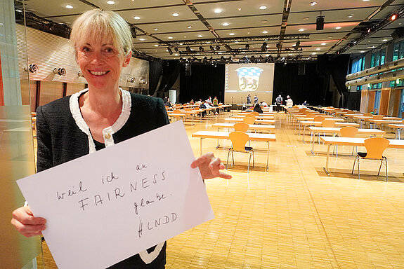 Bürgermeisterin Birgit Mooser-Niefanger hält ein Schild mit der Aufschrift: "weil ich an FAIRNESS glaube. #LNDD""