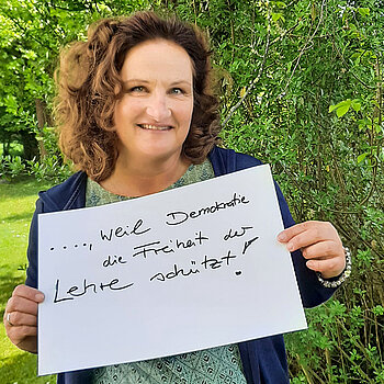 Susanne Röpke, Lehrerin am Camerloher Gymnasium hält ein Schild mit der Aufschrift: "Ich bin dabei, weil Demokratie die Freiheit der Lehre schützt!" Foto: privat