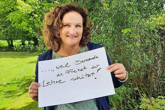 Susanne Röpke, Lehrerin am Camerloher Gymnasium hält ein Schild mit der Aufschrift: "Ich bin dabei, weil Demokratie die Freiheit der Lehre schützt!" Foto: privat