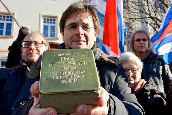 Peter Floßmann (VVN-BdA) präsentiert den Stolperstein, der vor dem Haus Wippenhauser Straße 18 an Emma Reißermeyer erinnert. (Foto: Stadt Freising)