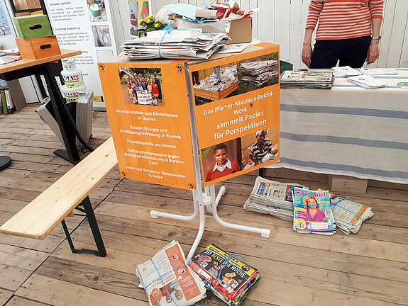 orangefarbene Infoplakate und Altpapierpacken