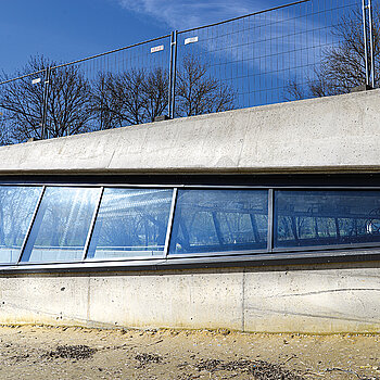 Das Bild zeigt das südliche Ende des Tunnelportals in einer Seitenansicht von außen mit der Schutzverglasung. (Foto: Stadt Freising)