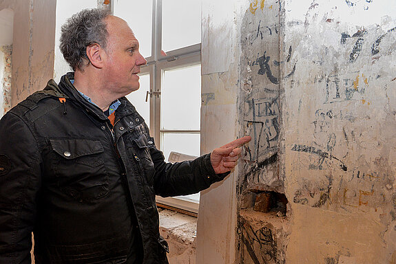 Ulrich Setzwein, Projektleiter für die Generalsanierung im Hochbauamt der Stadt, zeigt die jüngste Entdeckung: Graffitis an der Innenwand des Ostflügels. (März 2021/Foto: Stadt Freising)