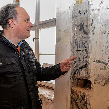 Ulrich Setzwein, Projektleiter für die Generalsanierung im Hochbauamt der Stadt, zeigt die jüngste Entdeckung: Graffitis an der Innenwand des Ostflügels.