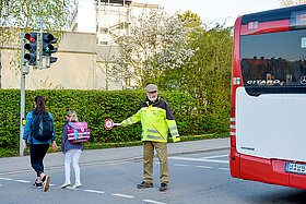 Ehrenamtliche Helferinnen und Helfer unterstützen Kinder dabei, sicher zur Schule und wieder nach Hause zu kommen. (Foto: Stadt Freising) Ehrenamtliche Helfer*innen wie Norbert May an der Rotkreuzstraße unterstützen Kinder dabei, sicher zur Schule und wieder nach Hause zu kommen. (Foto: Stadt Freising)