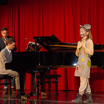 Das junge Talent Clara Pellmaier singt Fredericks Lied, begleitet von Lukas Voith am Klavier und Häns Czernik am Saxophon. 