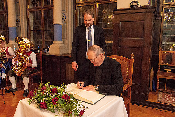 Ehre, wem Ehre gebührt: Weihbischof Bernhard Haßlberger trägt sich ins Gästebuch der Stadt Freising ein. (Foto: Stadt Freising)