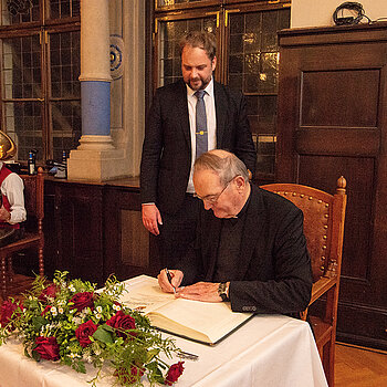 Ehre, wem Ehre gebührt: Weihbischof Bernhard Haßlberger trägt sich ins Gästebuch der Stadt Freising ein. (Foto: Stadt Freising)