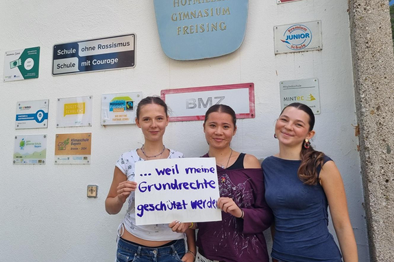 Amelia Herzer, Josefine Schimming und Mia Wengels feiern die Demokratie, weil die Grundrechte geschützt werden. Foto: Danzl Drei junge Frauen stehen vor dem Josef Hofmiller Gymnasium mit Schildern an der Wand. Unter anderem "Schule ohne Rassismus"