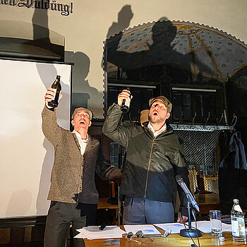 Zwei Männer, die Bierflaschen erheben.