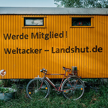 oranger Bauwagen mit der Aufschrift: Werde Mitglied! Weltacker-Landshut.de