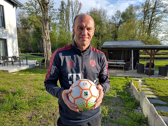 Der Freisinger Fußballweltmeister von 1990, Hans Pflügler, hält einen Fairtrade-Ball in der Hand. 