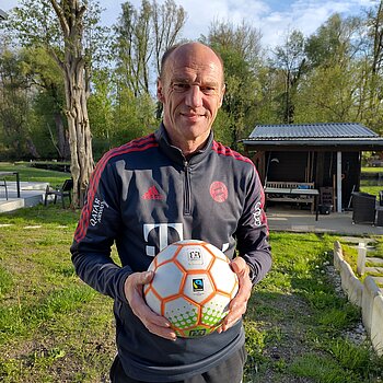 Der Freisinger Fußballweltmeister von 1990, Hans Pflügler, hält einen Fairtrade-Ball in der Hand. 