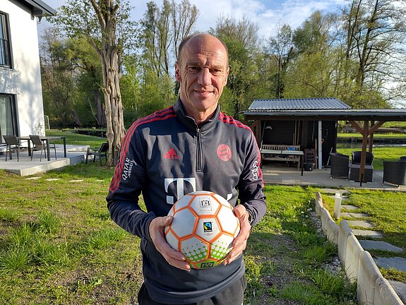 Der Freisinger Fußballweltmeister von 1990, Hans Pflügler, hält einen Fairtrade-Ball in der Hand. 