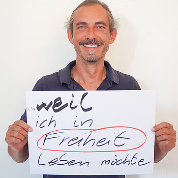 Stadtratsmitglied Jürgen Mieskes. Foto: Stadt Freising Ein Mann in einem schwarzen T-Shirt zeigt ein Schild mit der Aufschrift "weil ich in Freiheit leben möchte"