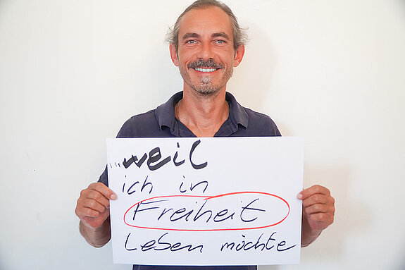 Stadtratsmitglied Jürgen Mieskes. Foto: Stadt Freising Ein Mann in einem schwarzen T-Shirt zeigt ein Schild mit der Aufschrift "weil ich in Freiheit leben möchte"