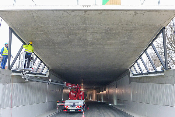 Blick in den (in Deckelbauweise) errichteten Tunnel sowie auf die Arbeiten für den Einbau des Stahlrahmens für die Verglasung am Südportal.