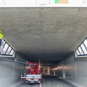 Blick in den (in Deckelbauweise) errichteten Tunnel sowie auf die Arbeiten für den Einbau des Stahlrahmens für die Verglasung am Südportal.