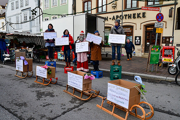 Aktivist*innen fordern auf der Straße mit Plakaten ein Lieferkettengesetz für verantwortungsvollen und fairen Handel.